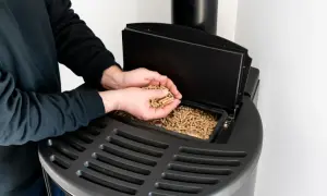 Mężczyzna wsypuje pellet do nowoczesnego pieca. Dofinansowanie do pieca na pellet to świetny sposób na ekologiczne ogrzewanie.
