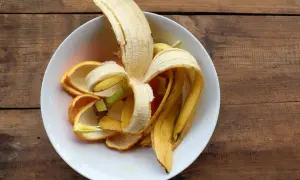 Skórki banana i pomarańczy w białej misce, gotowe na nawóz z banana.