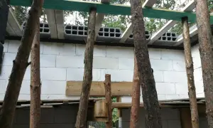 Budowa domu w toku. Drewniany podciąg podtrzymuje konstrukcję stropu nad ścianą z białych pustaków.