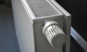 Biały grzejnik z termostatem. Dowiedz się, jak wyczyścić grzejnik z kurzu w środku, by zapewnić lepsze ogrzewanie.