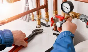 Instalator reguluje zawór przy manometrze, pracując nad systemem ogrzewania gazowego.