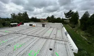 Gotowy do zalania strop filigran z zielonymi oznaczeniami, otoczony zielenią i chmurami.