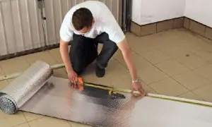 Mężczyzna mierzy materiał do ocieplenia bramy garażowej.