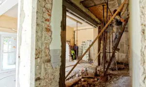 Remont wnętrza, gdzie pracownik na drabinie wzmacnia strop nad otworem w ścianie nośnej.