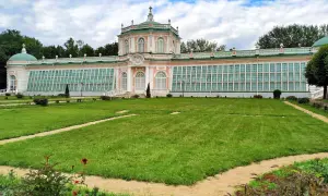 Przepiękny, różowo-zielony pałac z przeszklonymi ścianami, przypominający **ogród zimowy w domu**, otoczony jest zadbanym trawnikiem i alejkami.