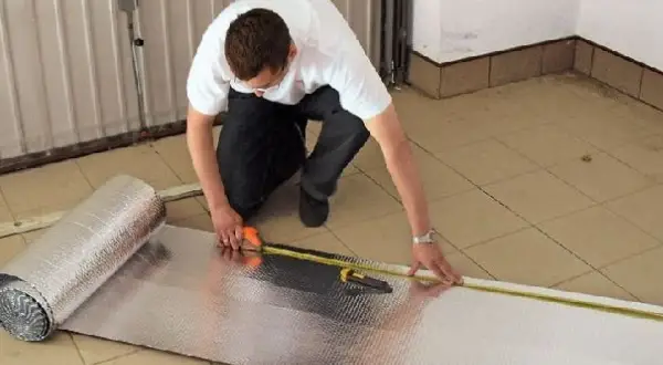 Mężczyzna mierzy materiał do ocieplenia bramy garażowej.
