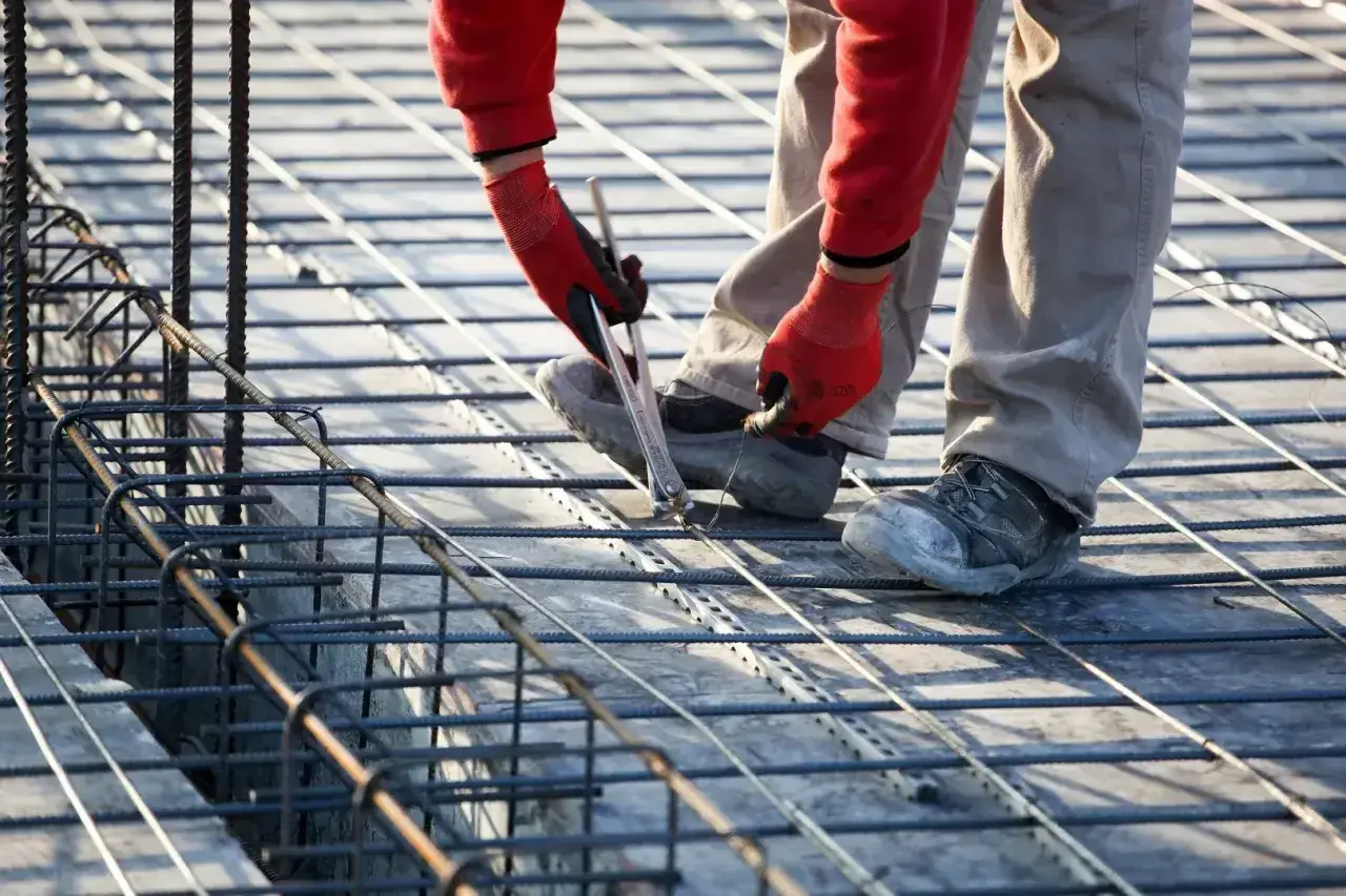 Budowlaniec wiąże zbrojenie, szacując, ile stali na fundament 100m2 będzie potrzebne.