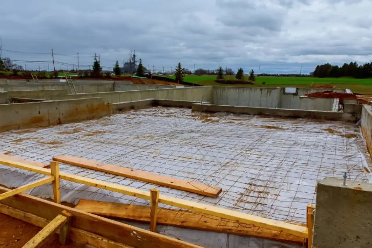 Betonowy fundament budowy, zbrojenie i folia izolacyjna czekają na wylanie.