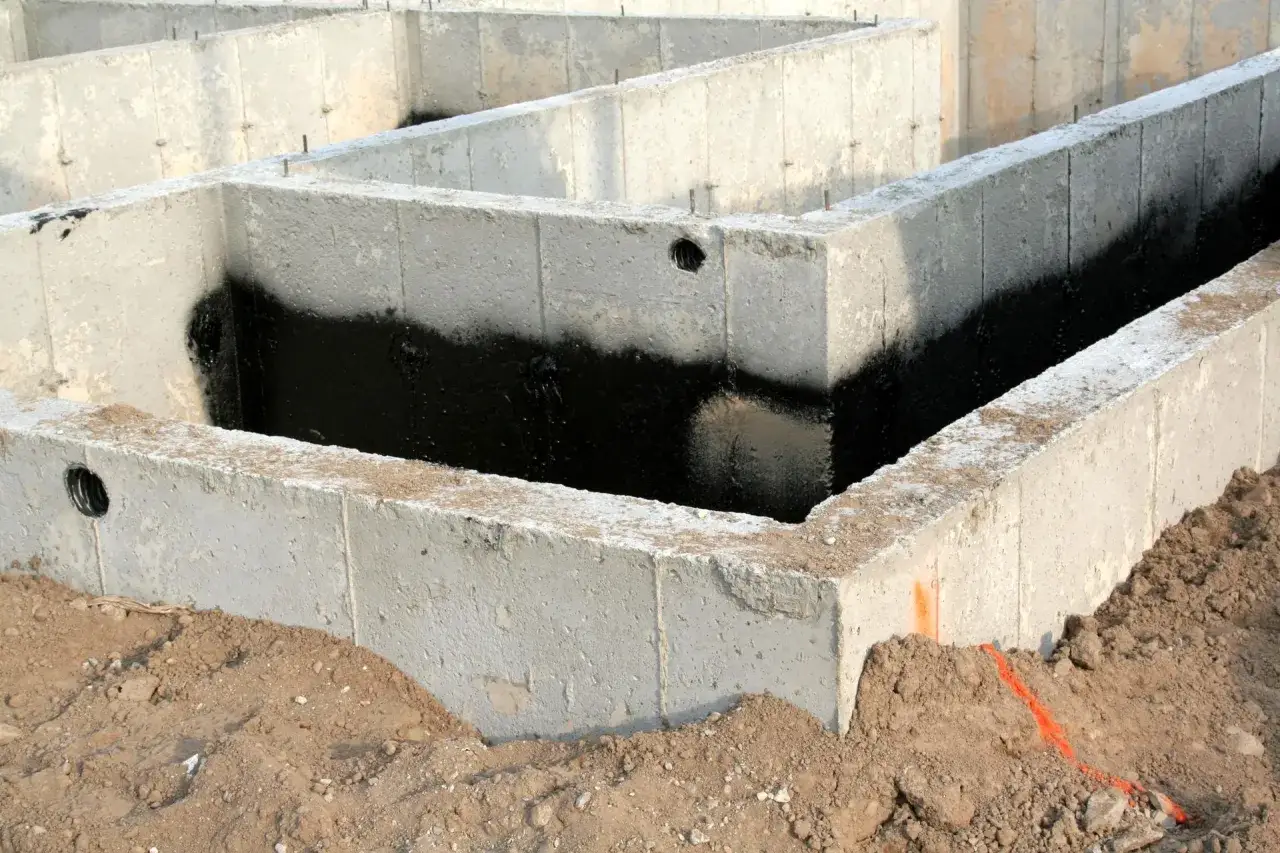 Fundament z bloczków betonowych, częściowo zaizolowany czarną masą. Widać otwory na przepusty. Jaki beton na fundament? Ten wygląda solidnie.